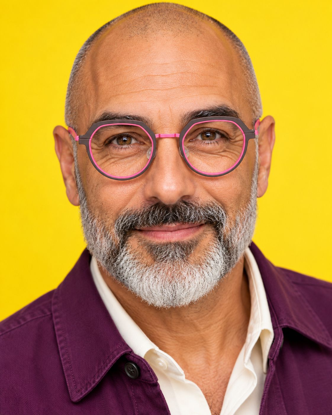 Homme à la barbe grise portant une monture graphite et rose vif sur fond jaune